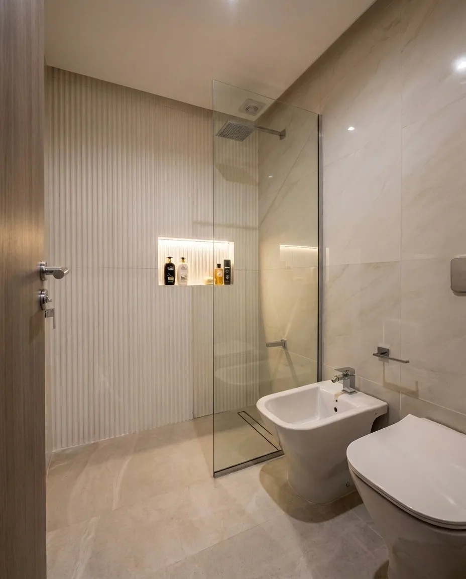 Baño principal de Casa PZ con ducha a nivel, mampara de vidrio y nicho iluminado